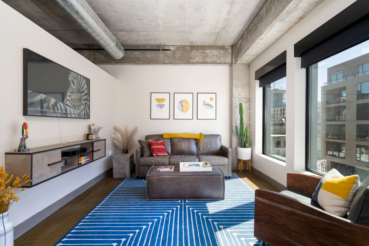Relax in your stylish loft with exposed concrete beams, comfortable seating, and vibrant art creating the perfect urban retreat.