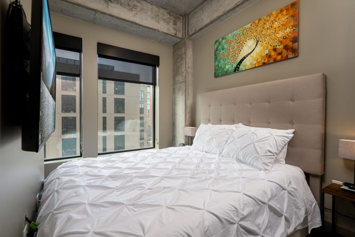 Drift off in your cozy bedroom featuring plush linens, modern art, and city views through expansive windows.