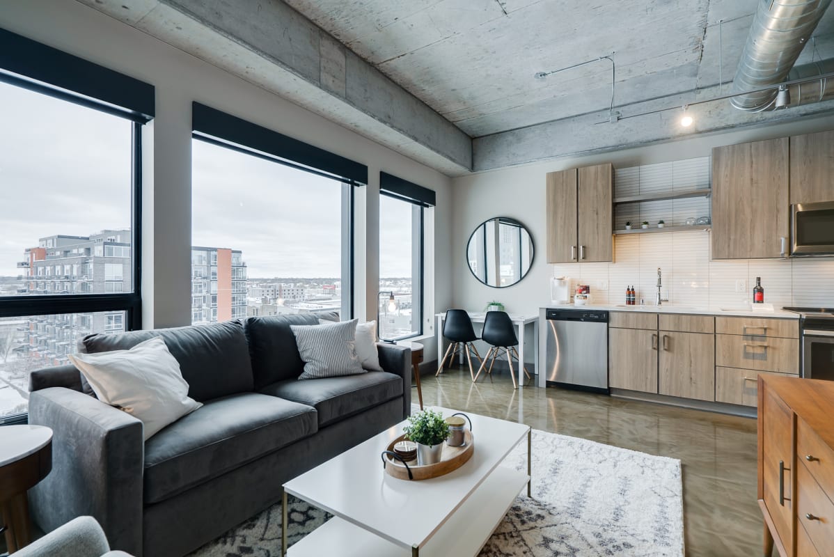 Relax in your sleek modern loft with floor-to-ceiling windows framing stunning city views while you unwind on the plush sectional sofa.