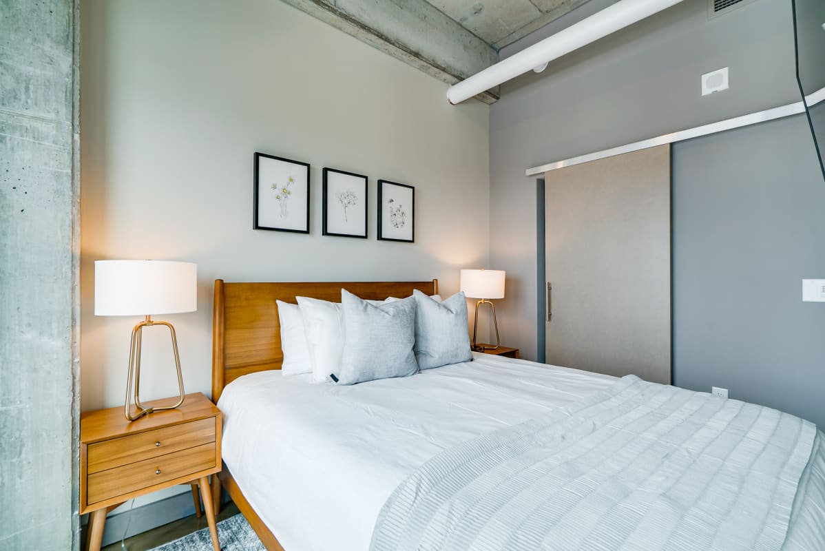 Sink into crisp white linens and soft pillows in your stylish bedroom, where warm lighting creates the perfect ambiance for rest.