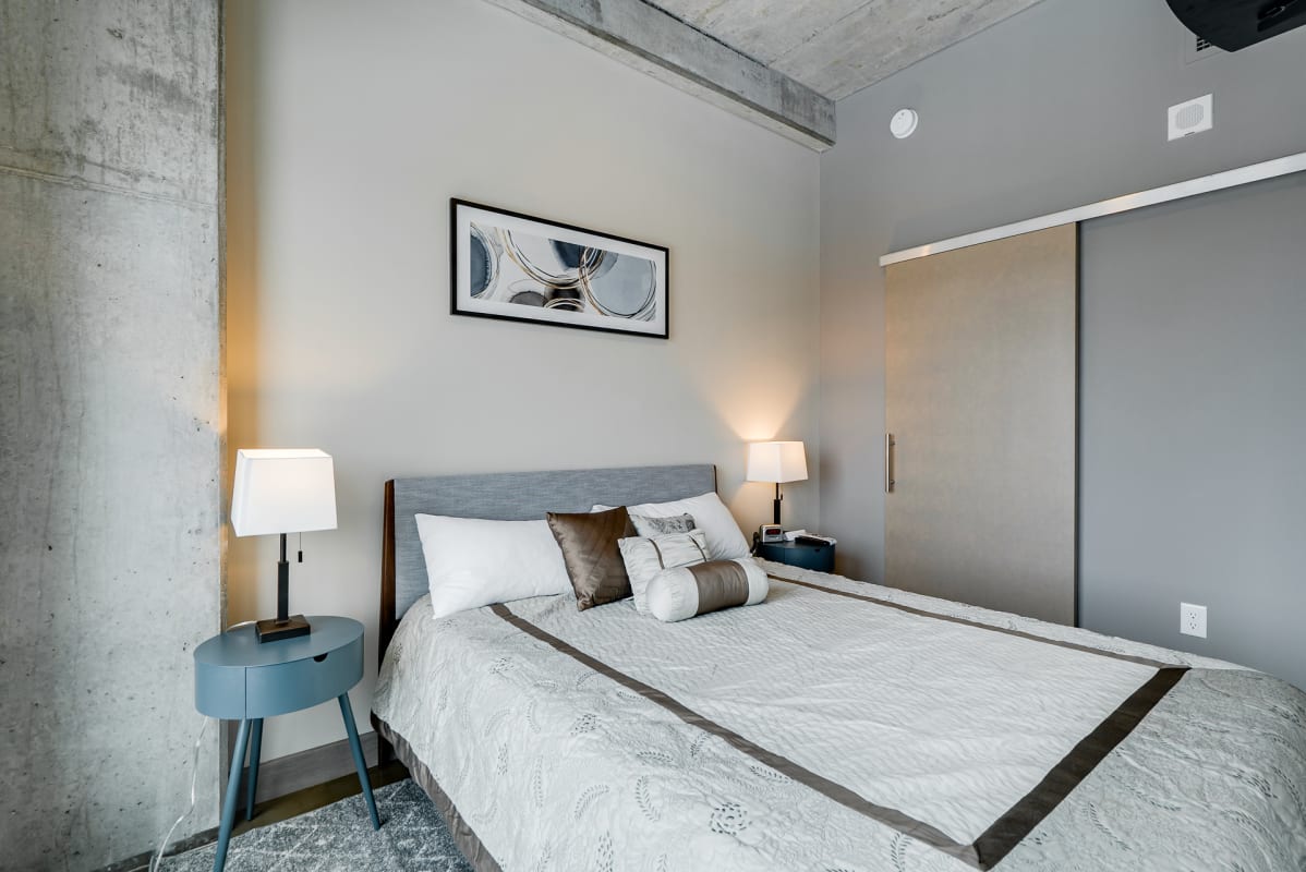 Rest in your modern loft bedroom with exposed concrete beams, contemporary art, and stylish furnishings creating an urban sanctuary.