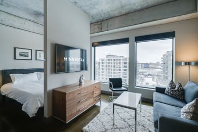 Contemporary studio interior with a bed, sofa, and large windows.