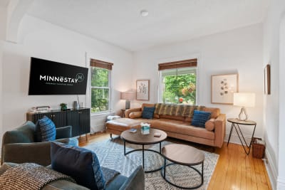 A cozy living room with leather furniture, decorative pillows, and large windows.