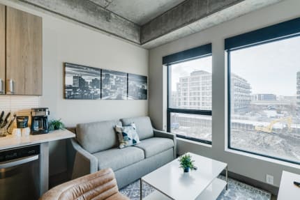 Modern living room with gray sofa, large windows, and a view of a construction site.