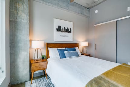 Contemporary bedroom with a made bed, artwork on the wall, and stylish lamps.
