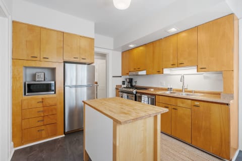Modern kitchen featuring light wood cabinets, stainless steel appliances, and a central island.