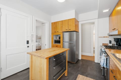 Contemporary kitchen with wooden cabinets, silver refrigerator, and central island.