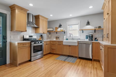 Modern kitchen with light wood cabinets and stainless steel appliances.