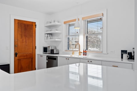 Modern kitchen with white countertops and a wooden door.