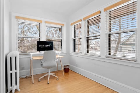 Home office with a desk, monitor, and large windows showcasing a winter view.