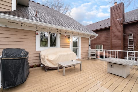 An outdoor patio featuring a grill, a covered seating area, and decorative string lights.