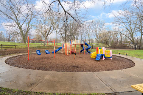 Playground with swings, slides, and climbing equipment in a park.