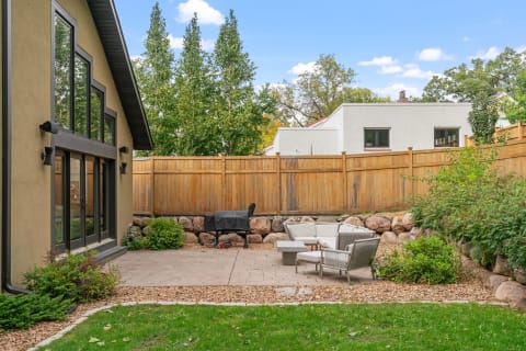 Outdoor patio area featuring circular seating, a gas grill, and a wooden fence.