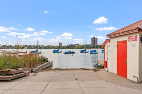 A tranquil lakeside scene featuring sailboats and a boat rental house.