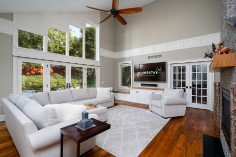 Spacious living room featuring a light gray sectional sofa, large windows, and a flat-screen TV.