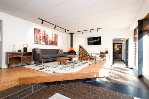 Stylish living room featuring a gray sectional sofa, abstract art, and a wood stove.