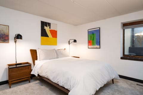 Cozy bedroom with modern decor and colorful art pieces on the walls.