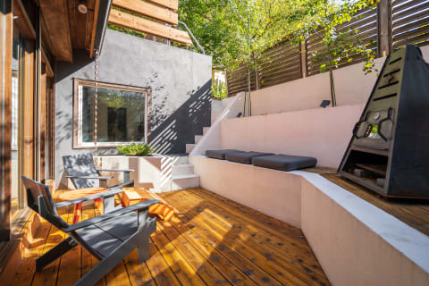 Modern outdoor seating area with wood deck and gray walls.
