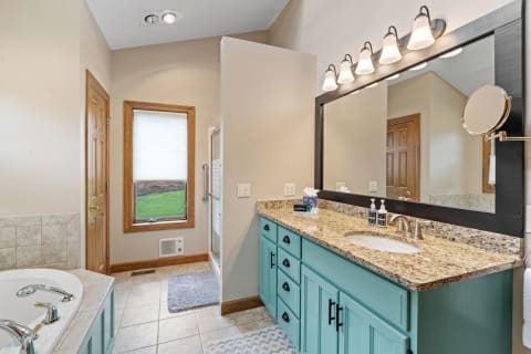 Modern bathroom with turquoise vanity and a window view of greenery.