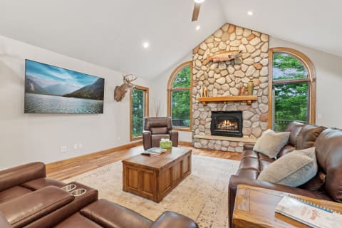 Cozy living room with stone fireplace, TV, and leather seating.