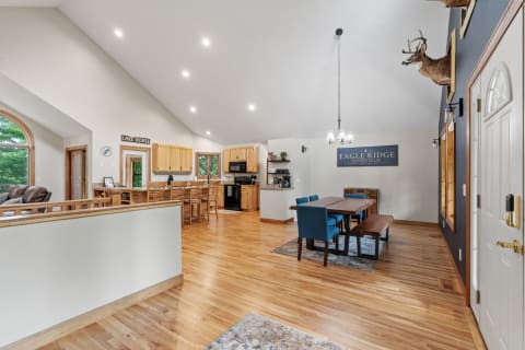 Spacious kitchen and dining area featuring vaulted ceilings, hardwood floors, and modern furnishings.