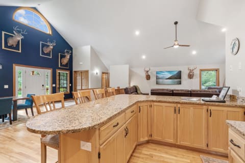 Open-concept living space featuring a granite bar, leather sofas, and framed deer heads.