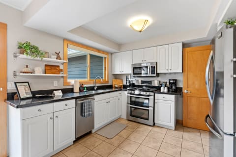 Modern kitchen with white cabinets, granite countertop, and stainless steel appliances.