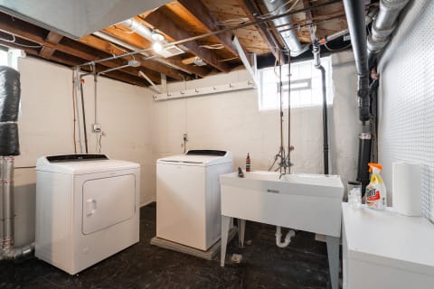 Basement laundry room with washing machines and a utility sink.