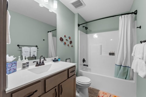A stylish bathroom with green walls, white towels, and a modern sink.
