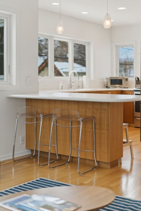 Modern kitchen with wood cabinetry, sleek countertop, and bar seating.