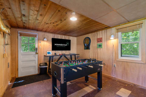Recreational room with foosball table, dartboard, and television for entertainment.