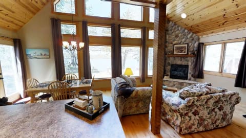 Interior of a lakeside cabin with a wooden ceiling and large windows overlooking the lake.