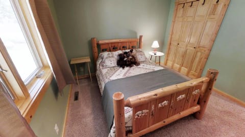 A wooden bed with a patchwork quilt and teddy bears in a rustic bedroom.