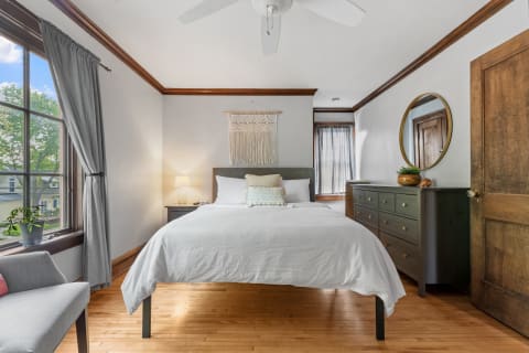 Cozy bedroom with a bed, macramé wall hanging, and wooden furniture.