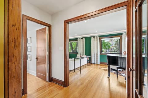 Interior view showcasing an open doorway, green accent wall, and modern furniture including a grand piano.