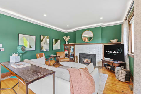 Modern living room with green walls, white brick fireplace, and stylish furniture.