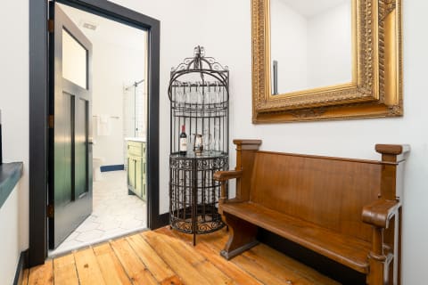 Cozy entryway with antique bench, decorative mirror, and wine rack.