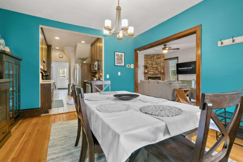 A dining table with a white tablecloth and gray placemats in a turquoise-walled dining area.