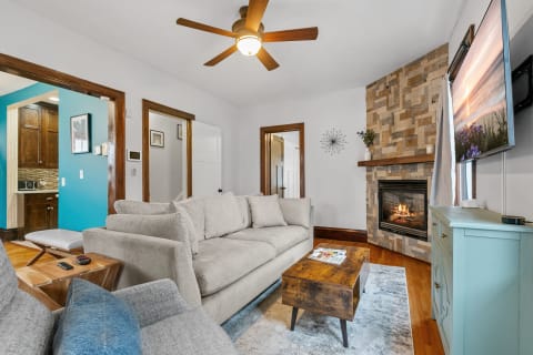 A cozy living room with a sectional sofa, wooden coffee table, and stone fireplace.