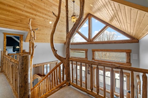 Loft area featuring wooden railing and large windows with beautiful views.