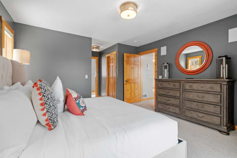 Modern bedroom featuring a stylish bed, decorative pillows, and a wooden dresser.