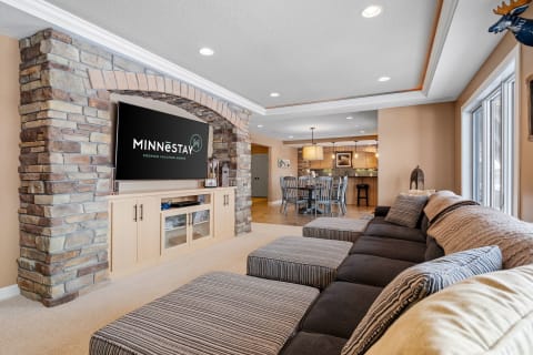A modern living room with a sectional couch, stone arch, and dining area in the background.