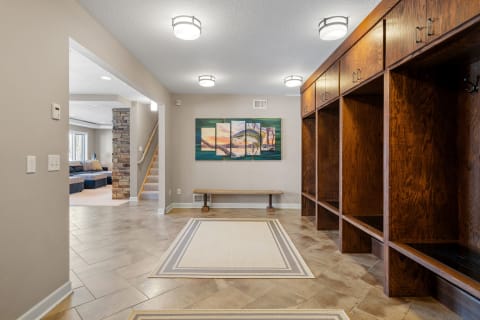 Spacious entryway with lockers, a bench, and a colorful wall painting.