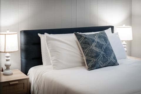 Neatly made bed with white linens and decorative pillows in a cozy bedroom setting.