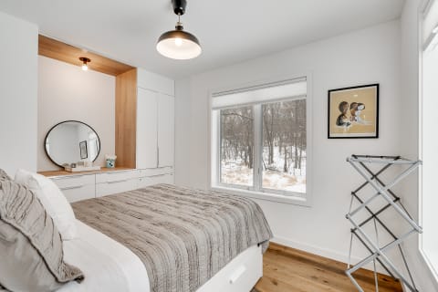 A contemporary bedroom with a large bed and a window showing a snowy landscape.
