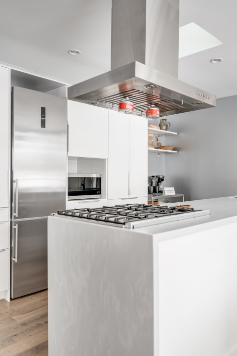 Modern kitchen featuring a sleek design with white cabinetry, a gas cooktop, and a refrigerator.