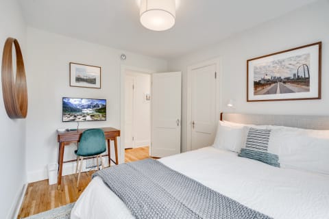Cozy bedroom with a bed, desk, and artwork on the walls.