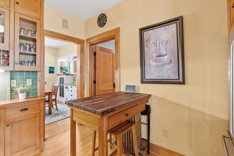 A warm kitchen featuring wooden elements, a coffee-themed art piece, and a cozy dining area.