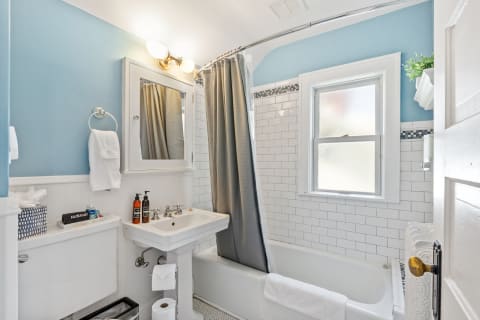 Cozy bathroom featuring light blue walls, a white bathtub, and elegant fixtures.