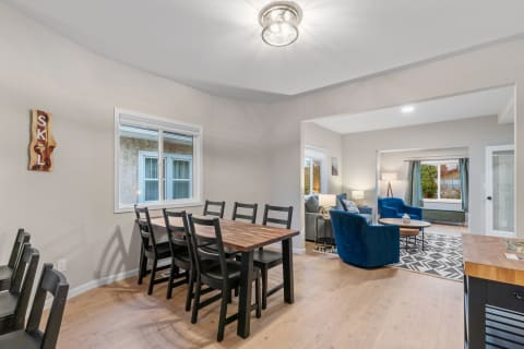 Open-concept dining area with a wooden table and blue accent chairs in the living room.